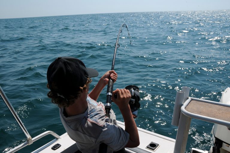 Man on a Boat Reeling in a Fish