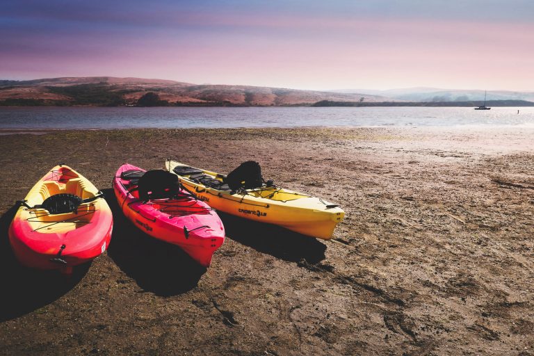 Three Sit On Top Kayaks on a Shore