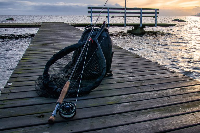 Bag and Fly Fishing Gear on Wooden Walkway